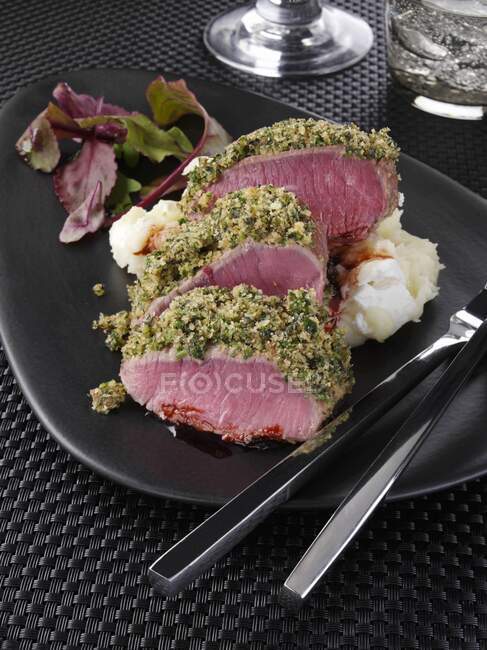 Un piatto di lombo di agnello in una crosta di erbe con verdure — Foto stock