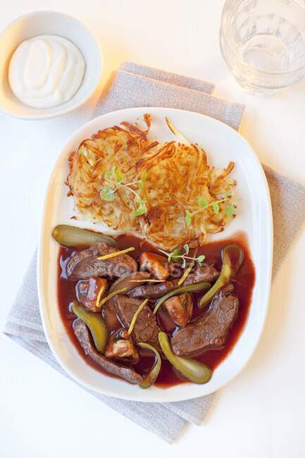 Beef stroganoff with potato rosti, gherkins and mushrooms in red wine sauce — Stock Photo