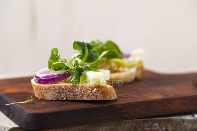 Rebanadas de baguette con aceite de oliva y ensalada (lechuga de cordero, berro, cebolla, lechuga iceberg, einkorn) - foto de stock