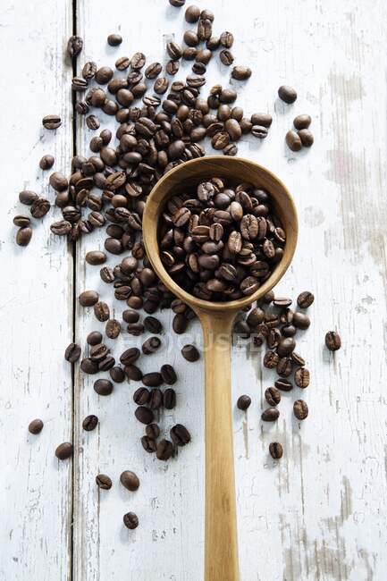 Coffee beans scattered on a table and in a wooden ladle - foto de stock