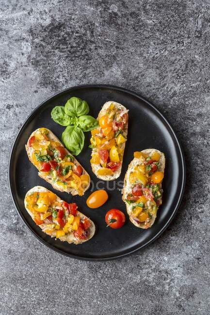 Bruschetta with colourful tomatoes and basil — Stock Photo