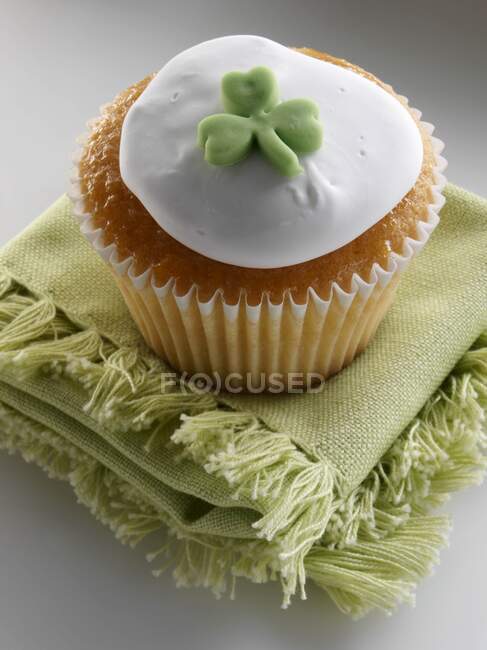 Cupcake with a green shamrock on top of the white icing — Stock Photo