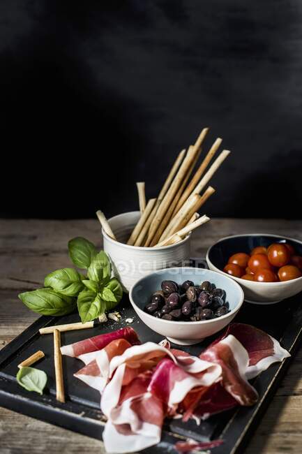 Parma ham, grissini, olives and tomatoes — Stock Photo