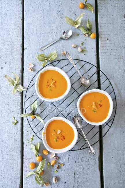 Carrot soup with physalis on wooden background — Stock Photo