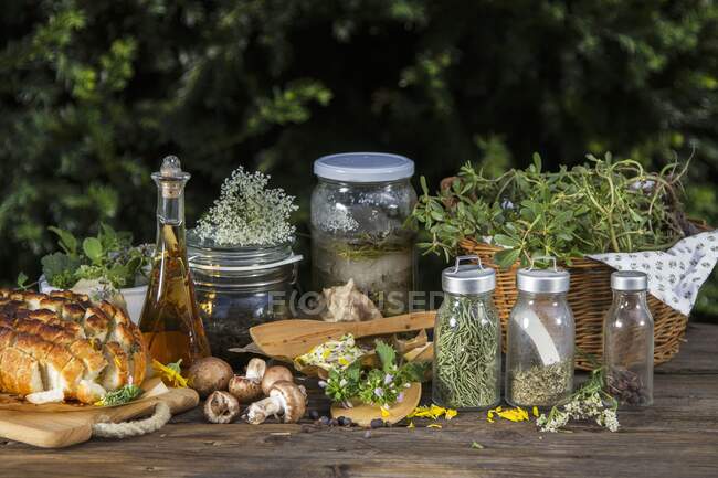Various wild herbs (fresh, dried and in jars), mushrooms, herb butter and pull apart bread — Stock Photo