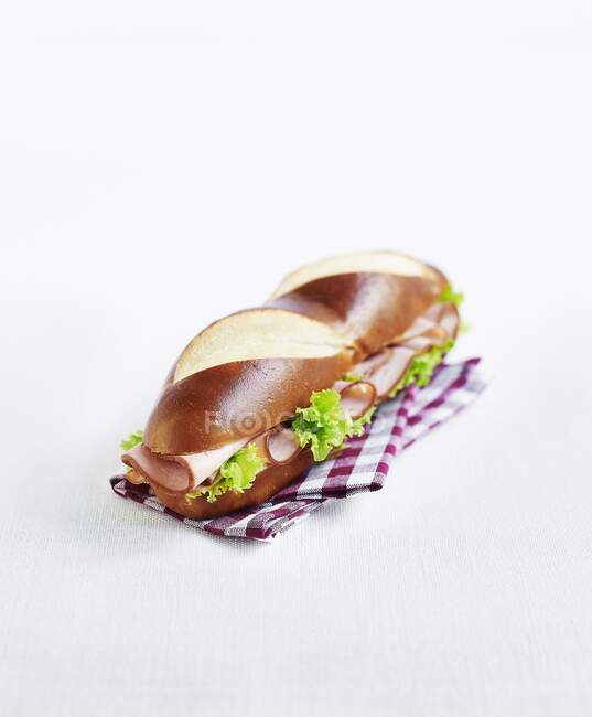 Un panino al pane alla liscivia con prosciutto e lattuga — Foto stock