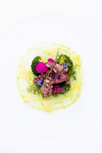 Eine Vorspeise mit mariniertem Oktopus, Zitrone und gegrillten Brokkoliröschen auf Salsa Verde mit Borretsch-Blüten — Stockfoto