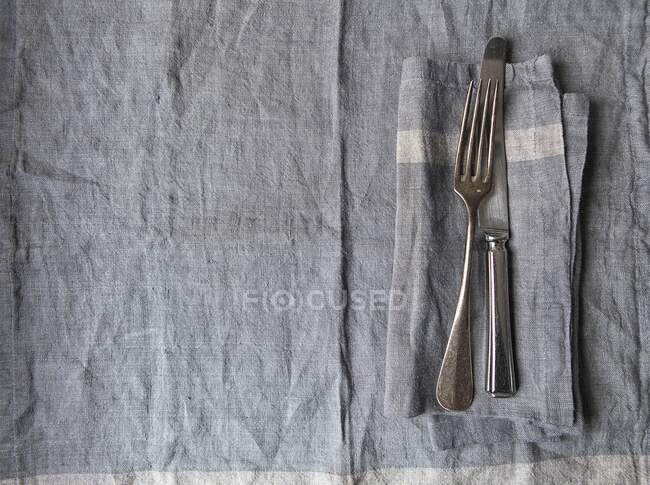 Серая льняная салфетка и винтажный серебряный нож и вилка — стоковое фото