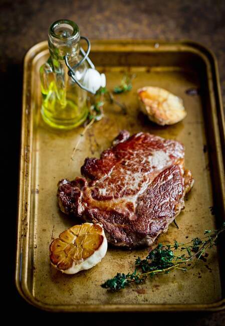 A steak with garlic on a roasting tray — Stock Photo