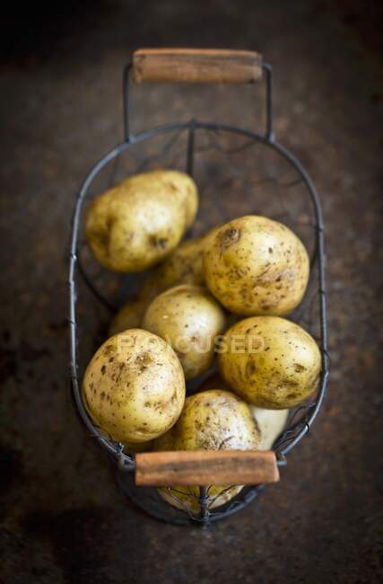 Fresh potatoes in a wire basket — Stock Photo