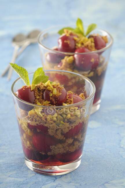 Cherry desserts in glasses with almond crumbs and pistachios — Stock Photo