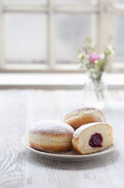 Jam doughnuts on a plate next to a window — Stock Photo