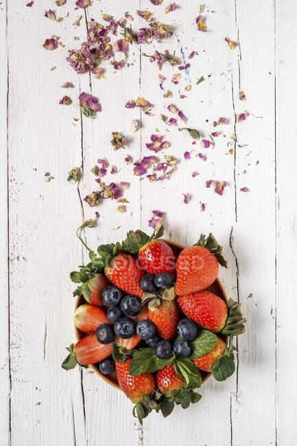 Mélange de fraises et de bleuets sur une vieille table en bois — Photo de stock
