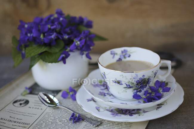 Uma xícara de café e violetas — Fotografia de Stock