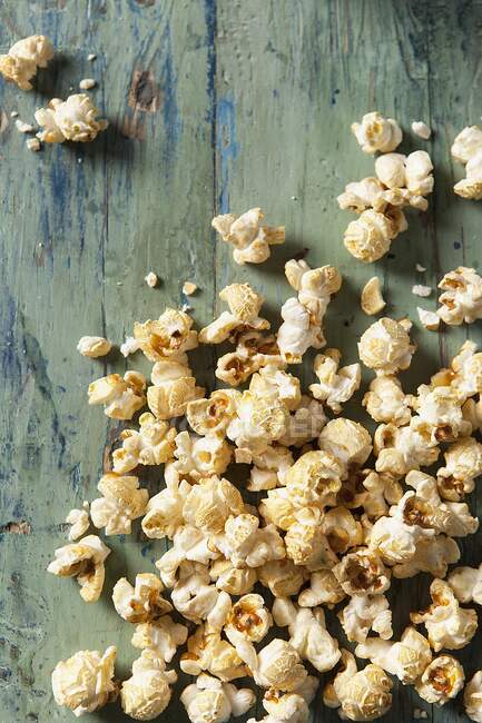 Popcorn covering an aqua blue green wooden surface — Stock Photo