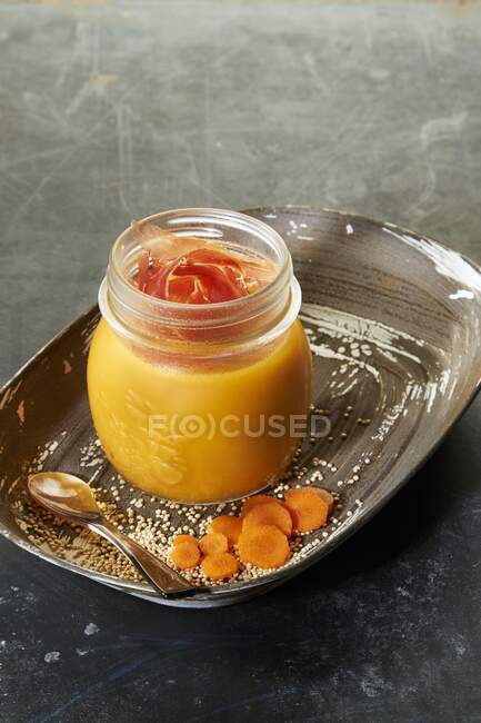 Creamy carrot and quinoa soup with raw ham in a glass jar — Stock Photo