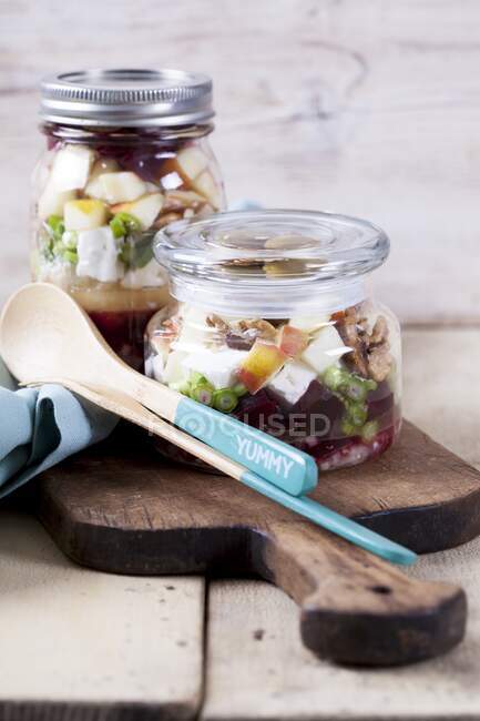 Beetroot with goat's cheese, apple, walnuts, olives and onions in a glass jar — Stock Photo