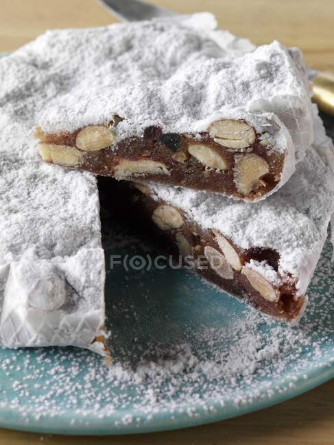 A whole Italian panforte cake with a slice on top — Stock Photo