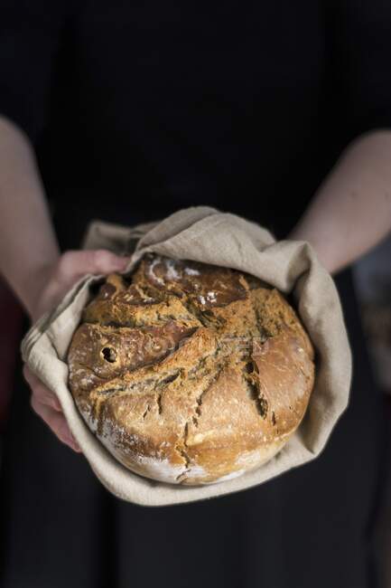 Hands holding clay pot baked beer bread — Stock Photo
