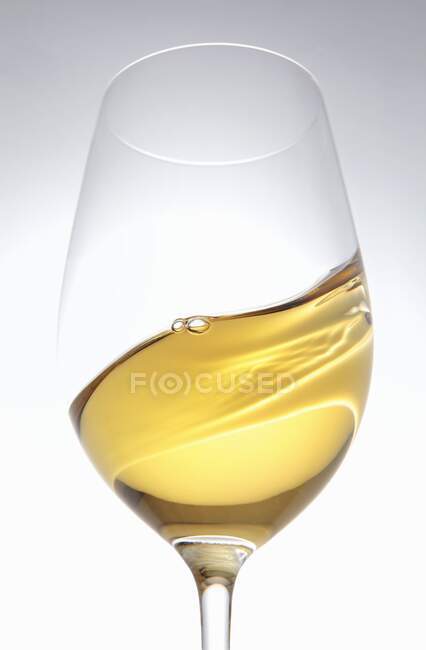 Un verre de vin blanc tourbillonné — Photo de stock