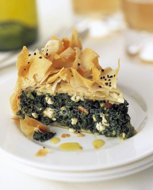 A slice of spinach filo pastry pie on a plate in a table setting — Stock Photo