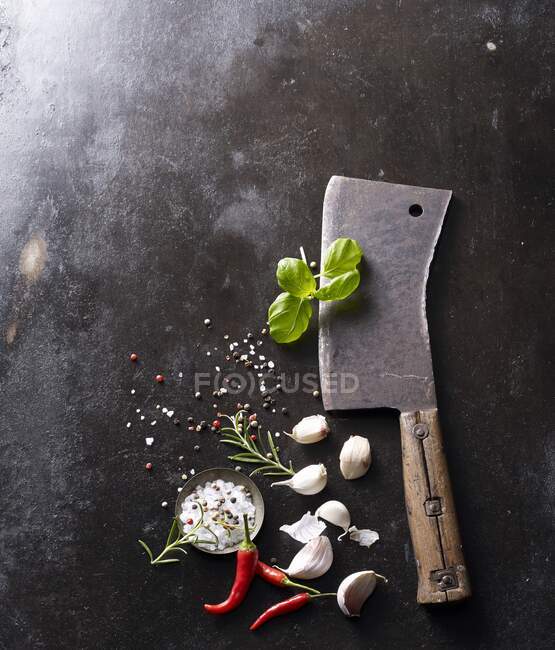 An old meat cleaver with garlic, salt, chili and basil on a baking tray — Stock Photo