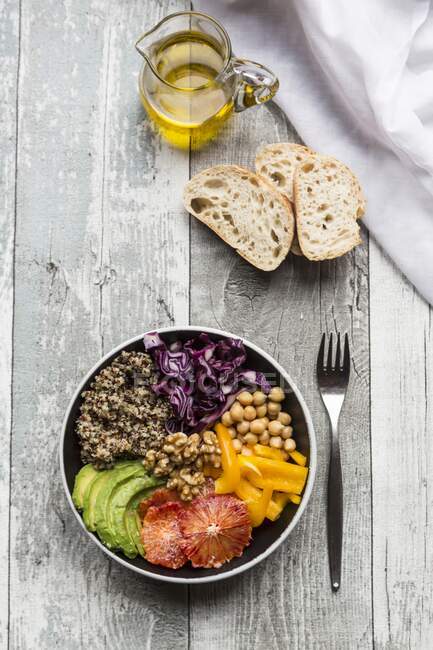Una ciotola di verdure con quinoa, ceci, avocado, peperoni, cavolo rosso e arance rosse — Foto stock