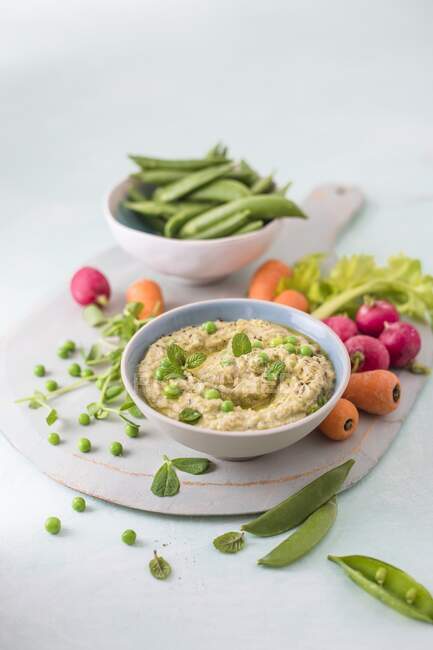 Houmous aus Kichererbsen, Erbsen mit Minze und Tahini, frisches Gemüse und Dip auf der Seite — Stockfoto