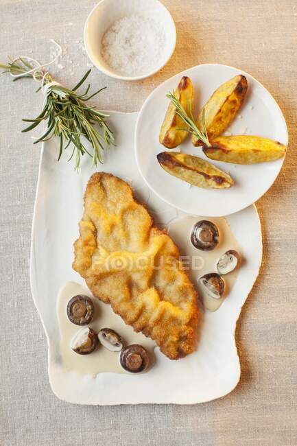 Schnitzel in white wine and mushroom sauce with potato wedges — Stock Photo