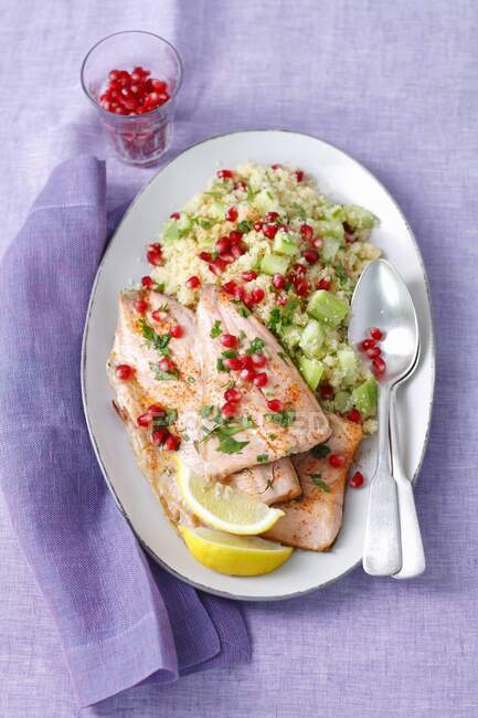 Fried salmon trout with cooscous and cucumber salad and pomegranate seeds — Stock Photo