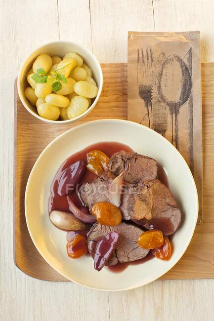 Carne asada con albaricoques, patatas y chalotes - foto de stock