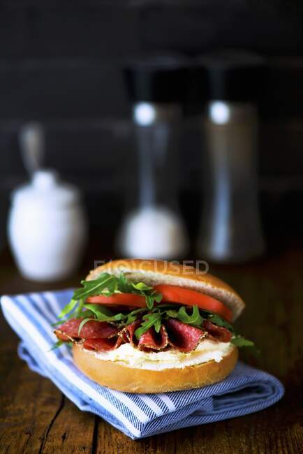 Bagel with cream cheese, pepper salami, rocket and tomatoes — Stock Photo