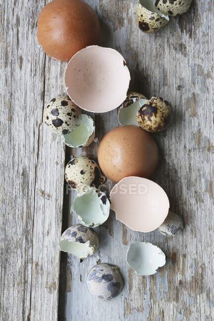 Huevos de pollo y codorniz agrietados en superficie de madera rústica - foto de stock