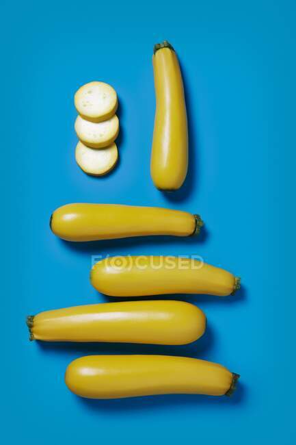 Varios zucchinis amarillos, enteros y cortados en rodajas - foto de stock