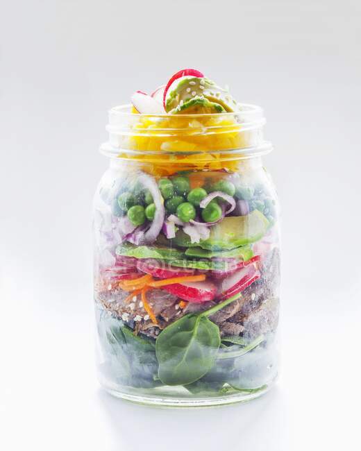 Vegetable salad with peas, avocado, radishes, bread and spinach in a glass jar — Stock Photo