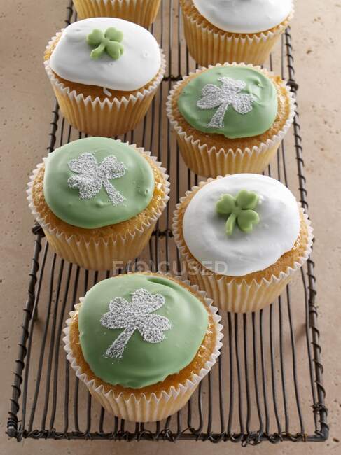 Cupcakes con tréboles verdes encima de glaseado blanco - foto de stock