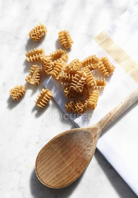 Pasta (radiatori, armoniche) and a wooden spoon — Stock Photo