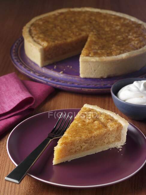 Eine Scheibe Baumkuchen auf einem Teller mit der ganzen Torte dahinter — Stockfoto