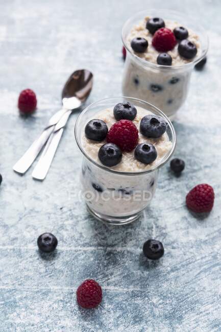 Porridge with raspberries and blueberries in two glasses — Stock Photo