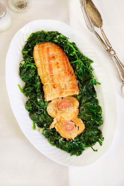 Chicken roulade with ham and spices on sauted spinach — Stock Photo