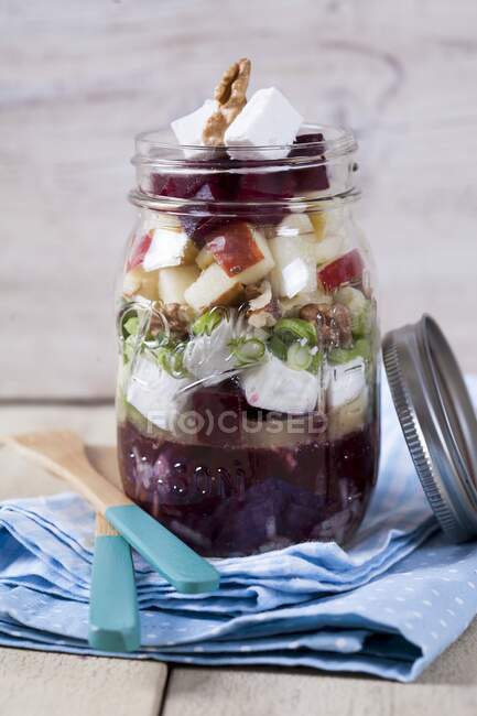 Beetroot with goat's cheese, apple, walnuts, olives and onions in glass jar — Stock Photo