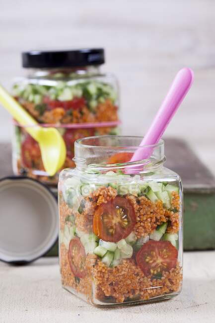 Салат из булгура с гранатовым сиропом, луком, огурцом, помидорами, петрушкой и мятой в стеклянных банках — стоковое фото