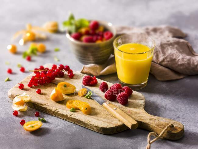Fresh fruit on a chopping board and a glass of fruit juice — Stock Photo