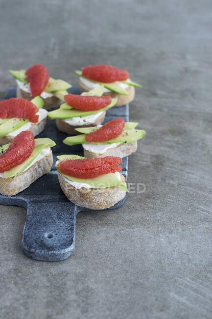 Crostini topped with chevre cheese, avocado and grapefruit — Stock Photo