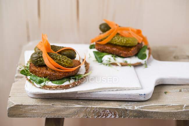 Vegan burger with tofu patty, gherkins, lamb's lettuce, carrot and cress — Stock Photo