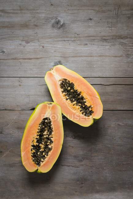 Halved papaya fruit on a wooden table — Stock Photo