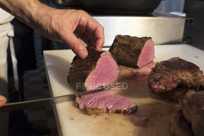 Um filete de carne de bovino a ser fatiado — Fotografia de Stock