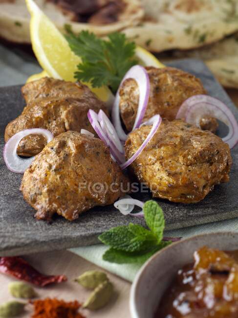 Chicken tikka with red onion slices and spices — Stock Photo