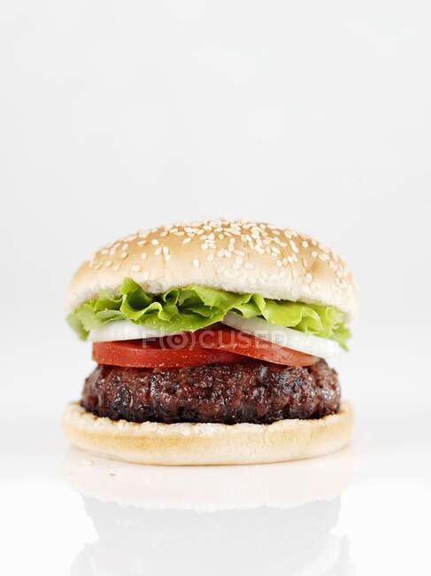 Una hamburguesa con tomates, cebollas y lechuga - foto de stock