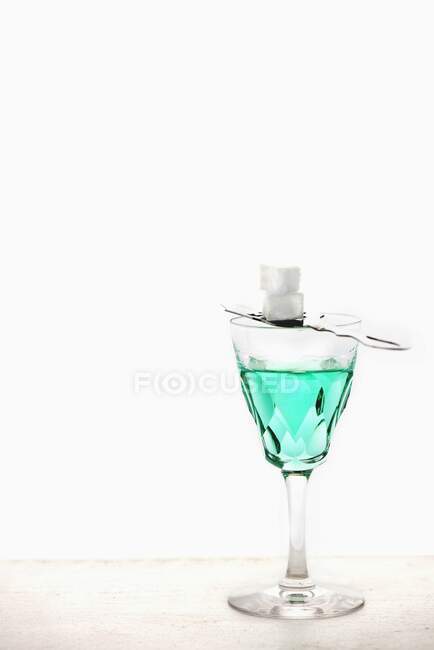 Absinthe avec une cuillère à absinthe et des cubes de sucre dans un verre de cristal — Photo de stock